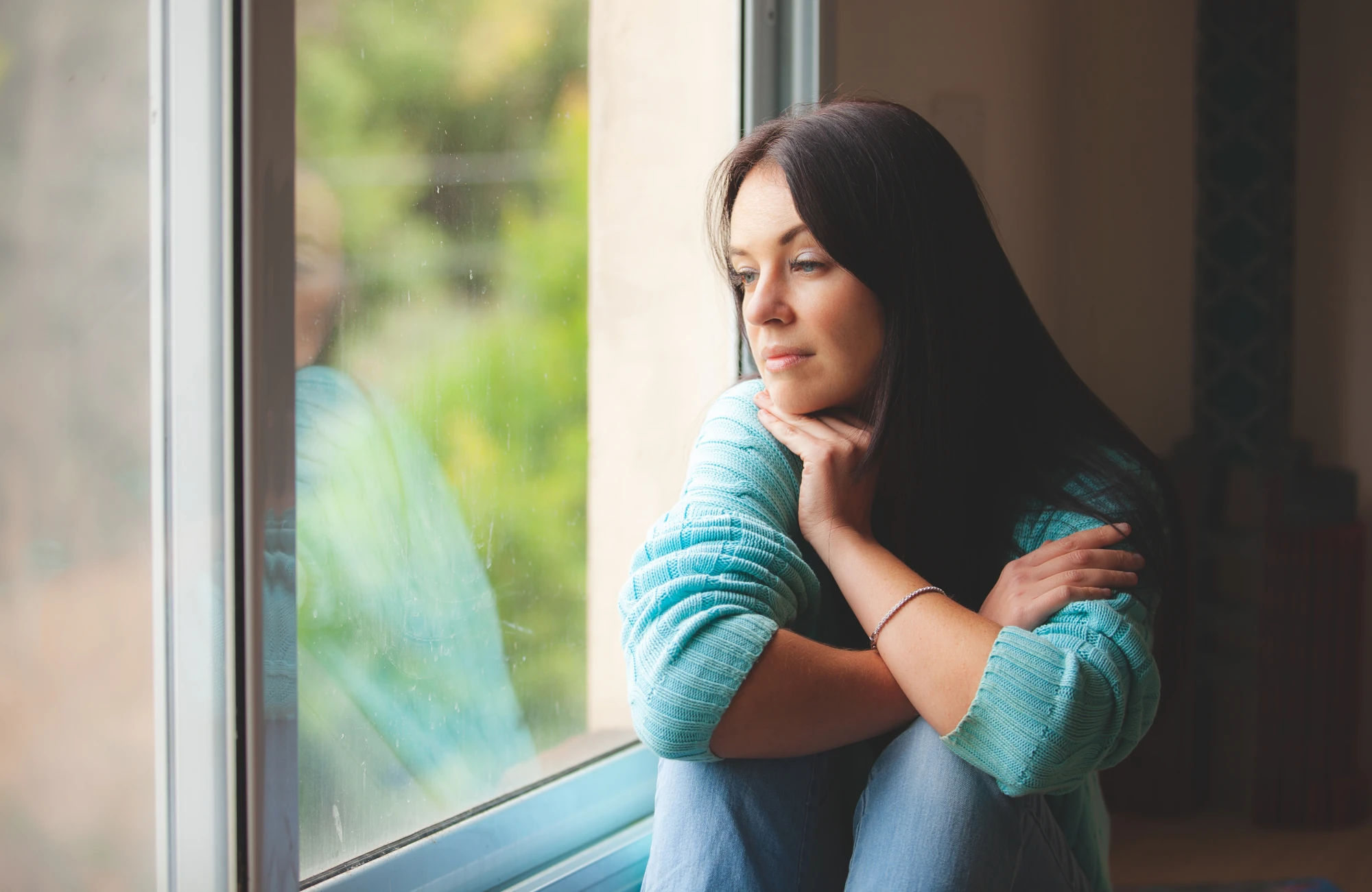 Woman reflecting by a window while working through relationship patterns in recovery