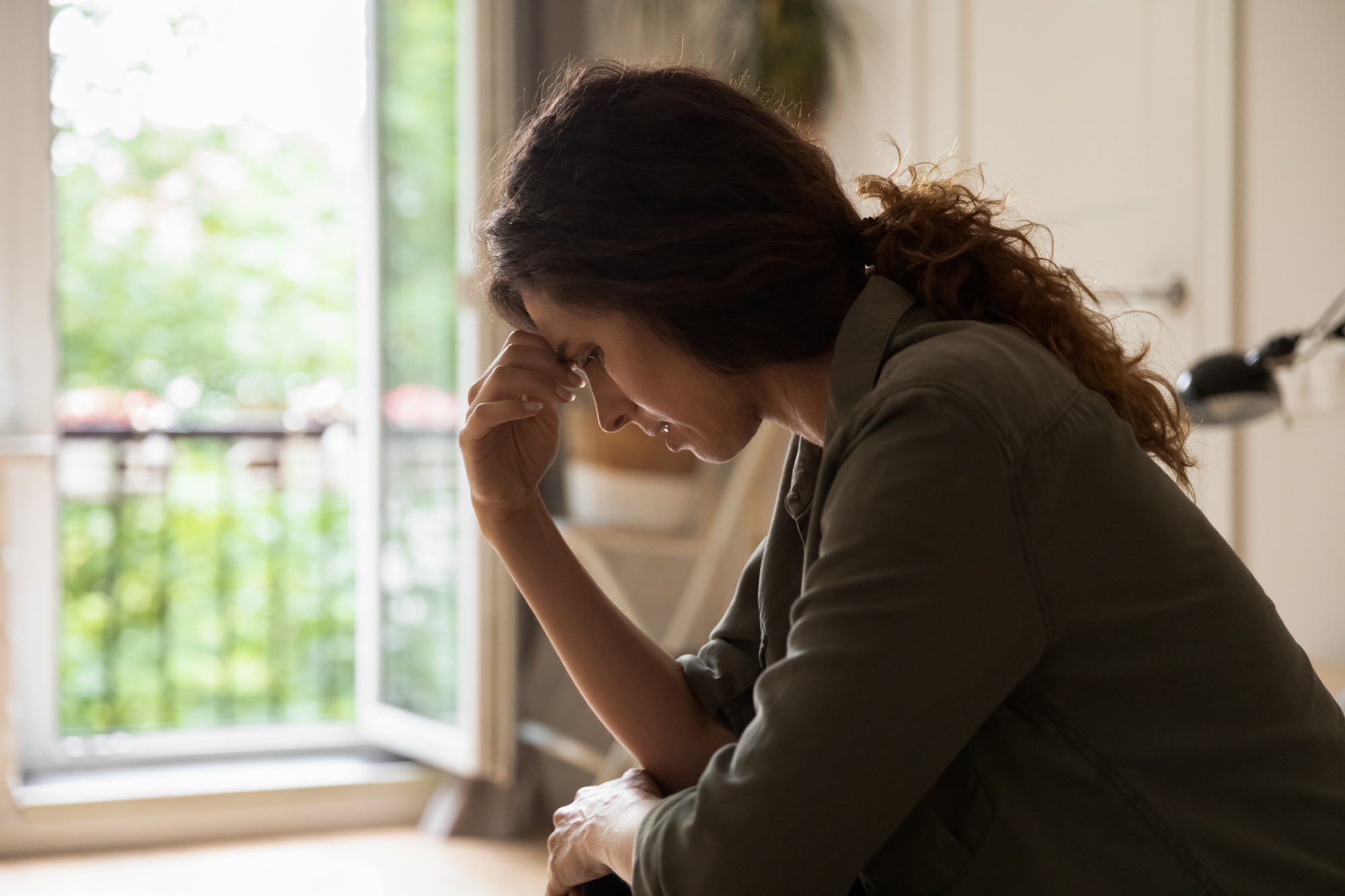 Woman in her forties or fifties at home in the evening, thoughtful or weary, calm domestic setting