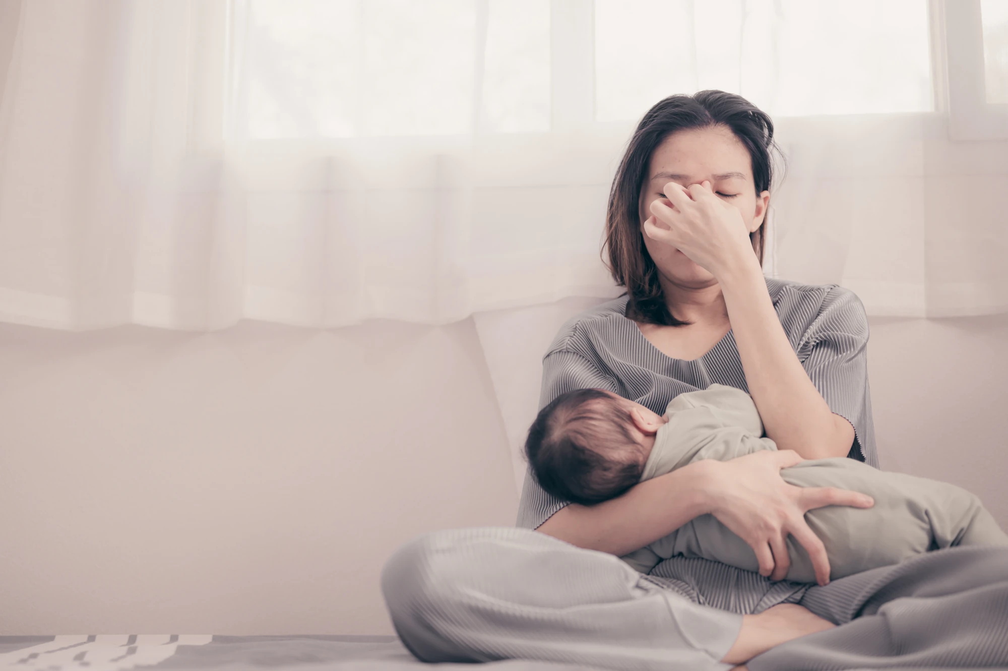 Tired new mother at home with her baby during the postpartum period
