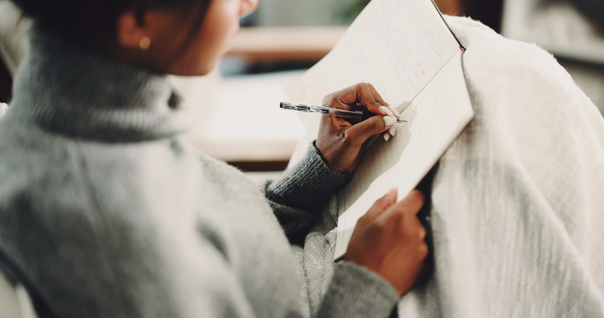 Woman writing in a notebook at home
