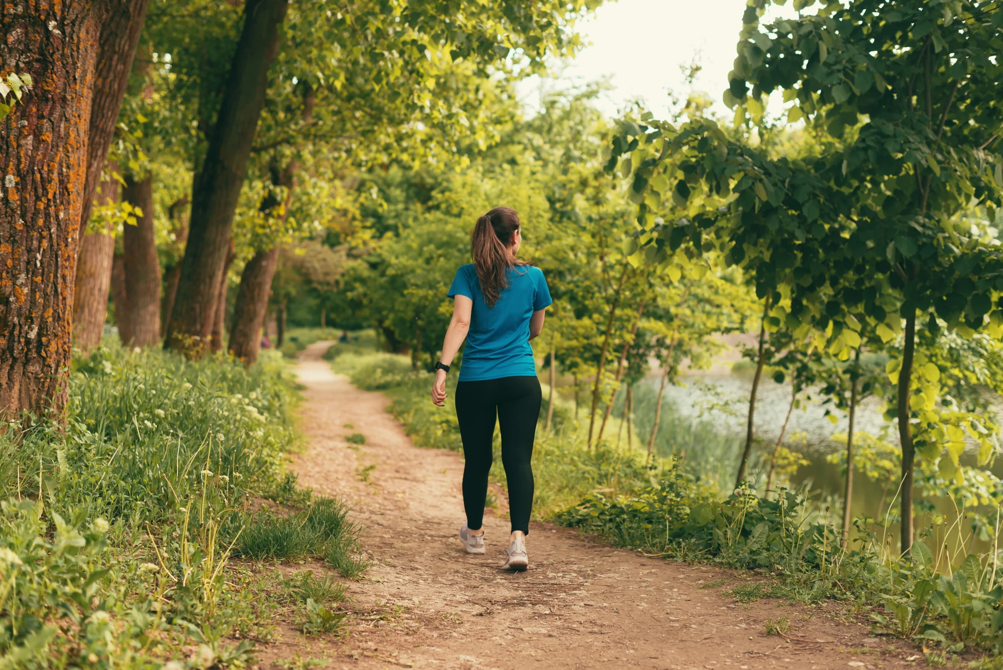 Alt text: A woman walks along an outdoor path on a sunny day.