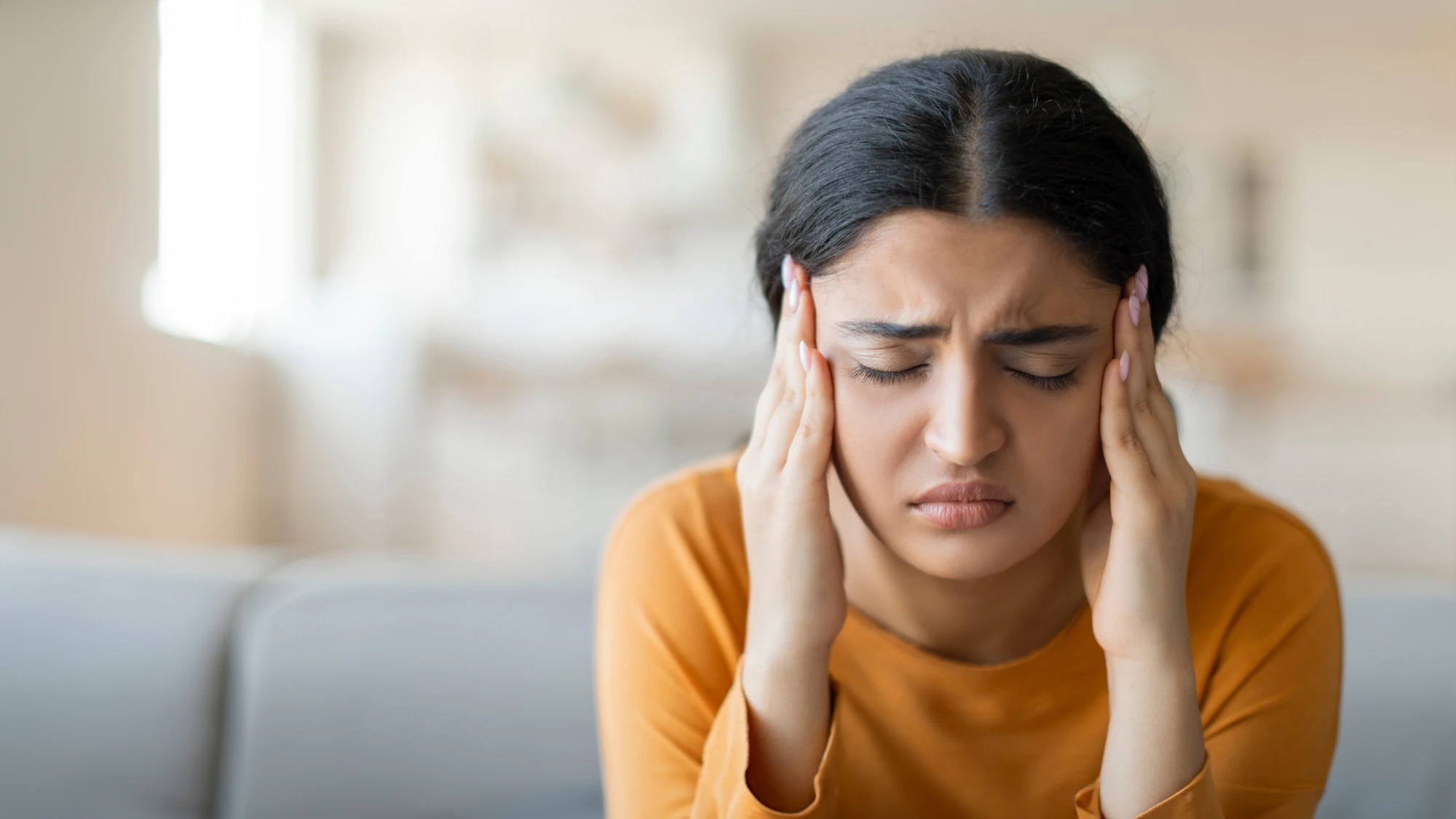 Woman holding her head with a pained expression